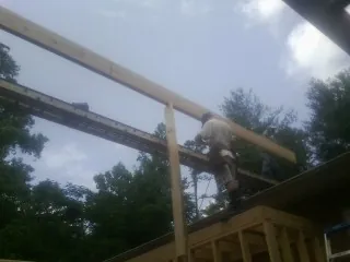 Carpenter setting a ridge beam over a new addition frame — Ice Dam Removal by Roofing Brothers in Peralta