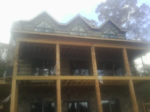 Dormers and porch framing on a large log home under construction — Roof Coating work by our crew in Peralta