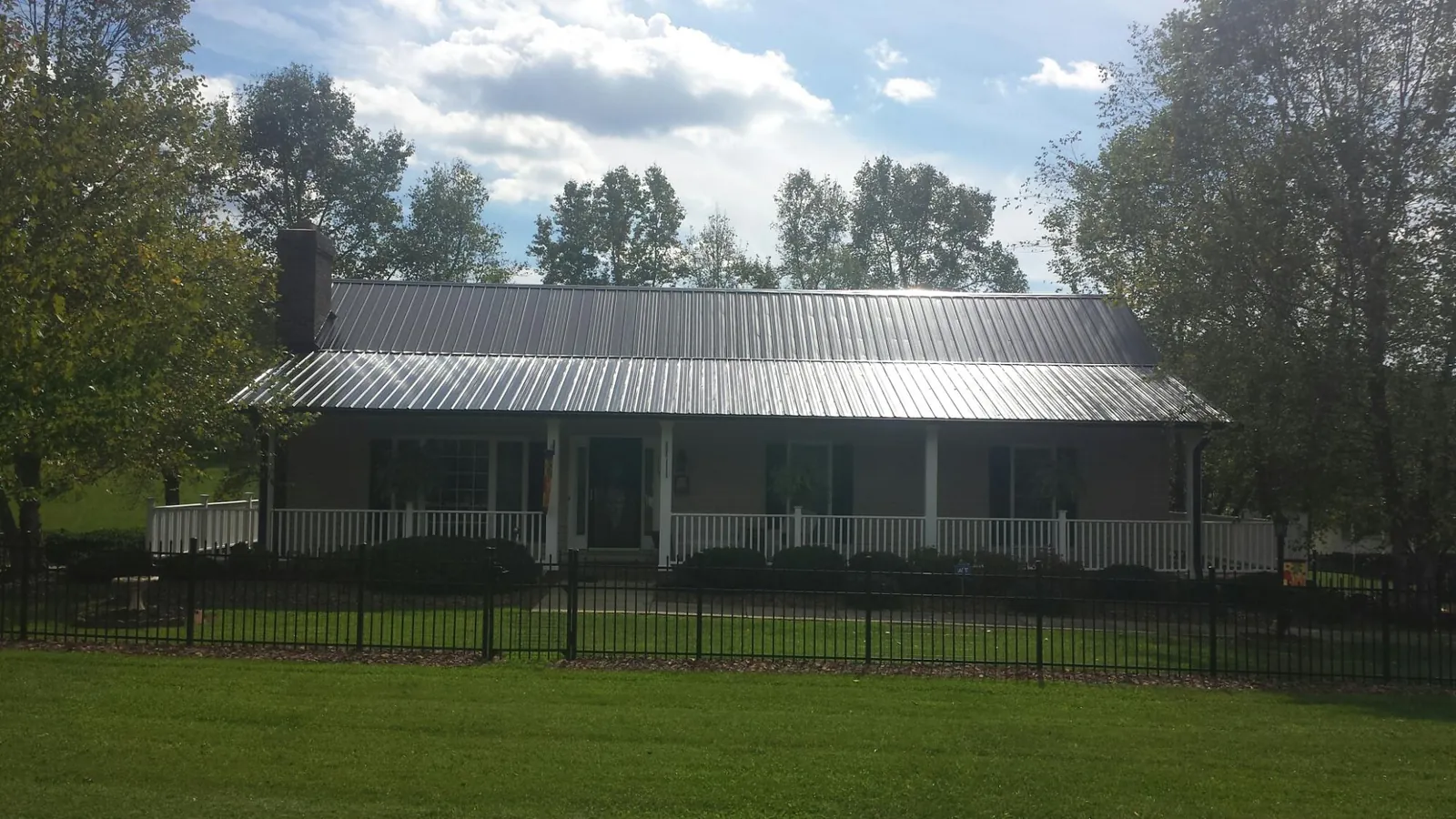 Gray metal roof on a brick ranch with a full width front porch — Gutter Guard Installation work by our crew in Peralta