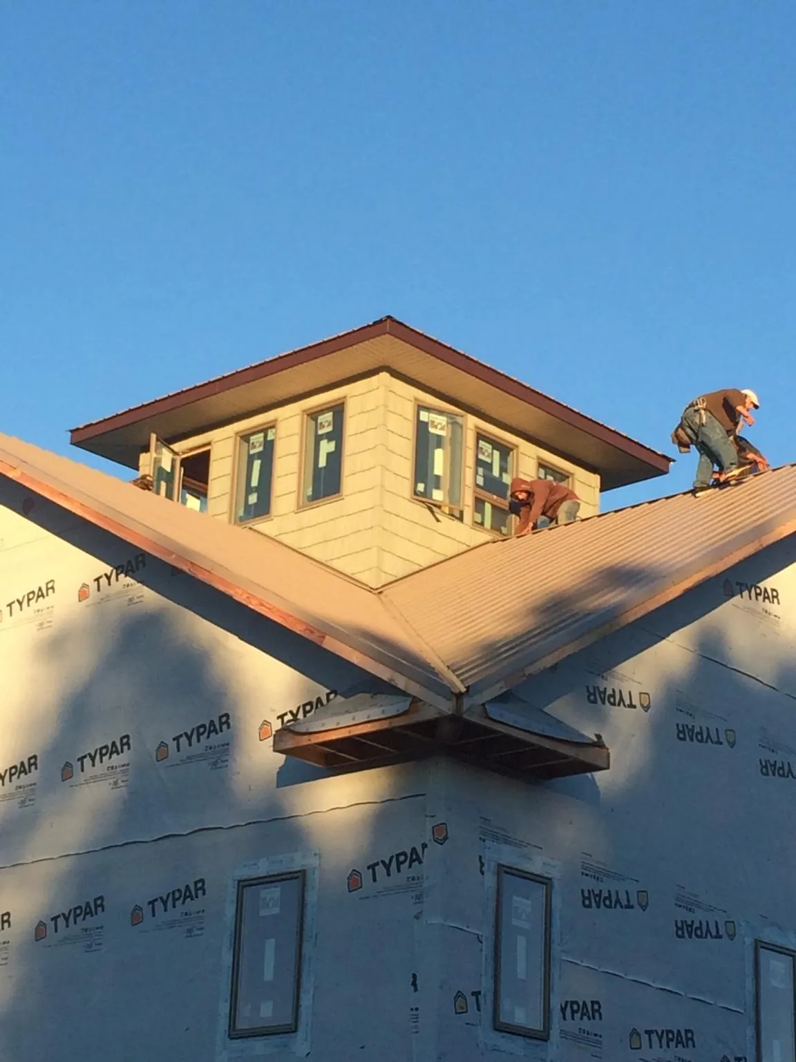 Roofers working around a rooftop cupola on a new metal roof at sunset — Roof Waterproofing in Peralta by Roofing Brothers